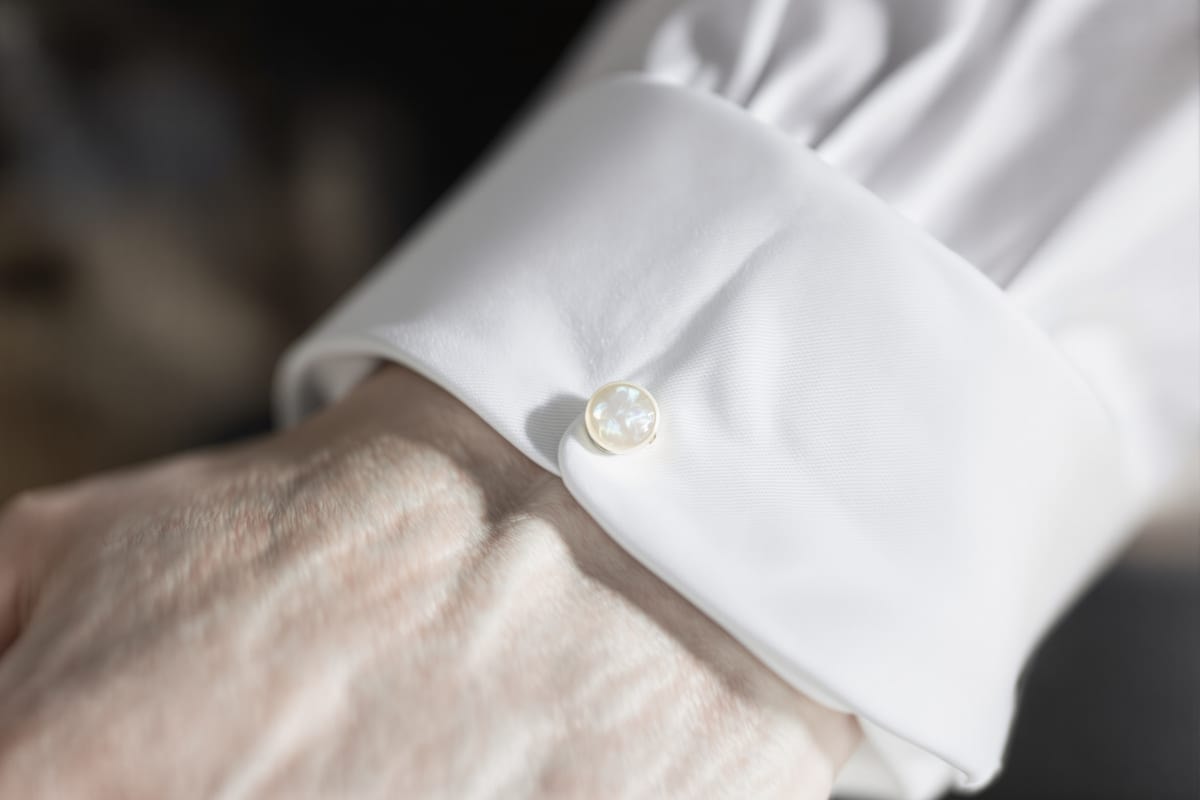 A white cotton double cuff fastened edge to edge with a mother-of-pearl cufflink