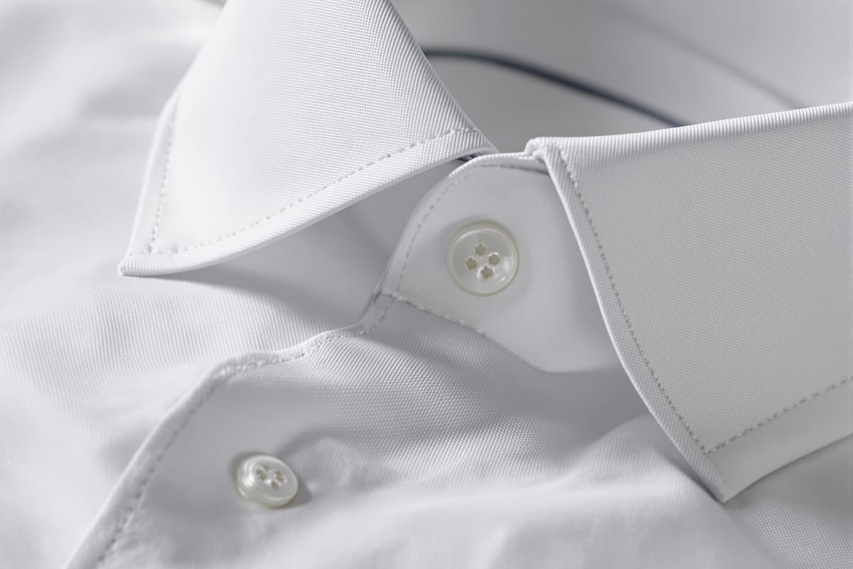 Collar and placket detail of a white cotton dress shirt with mother-of-pearl buttons
