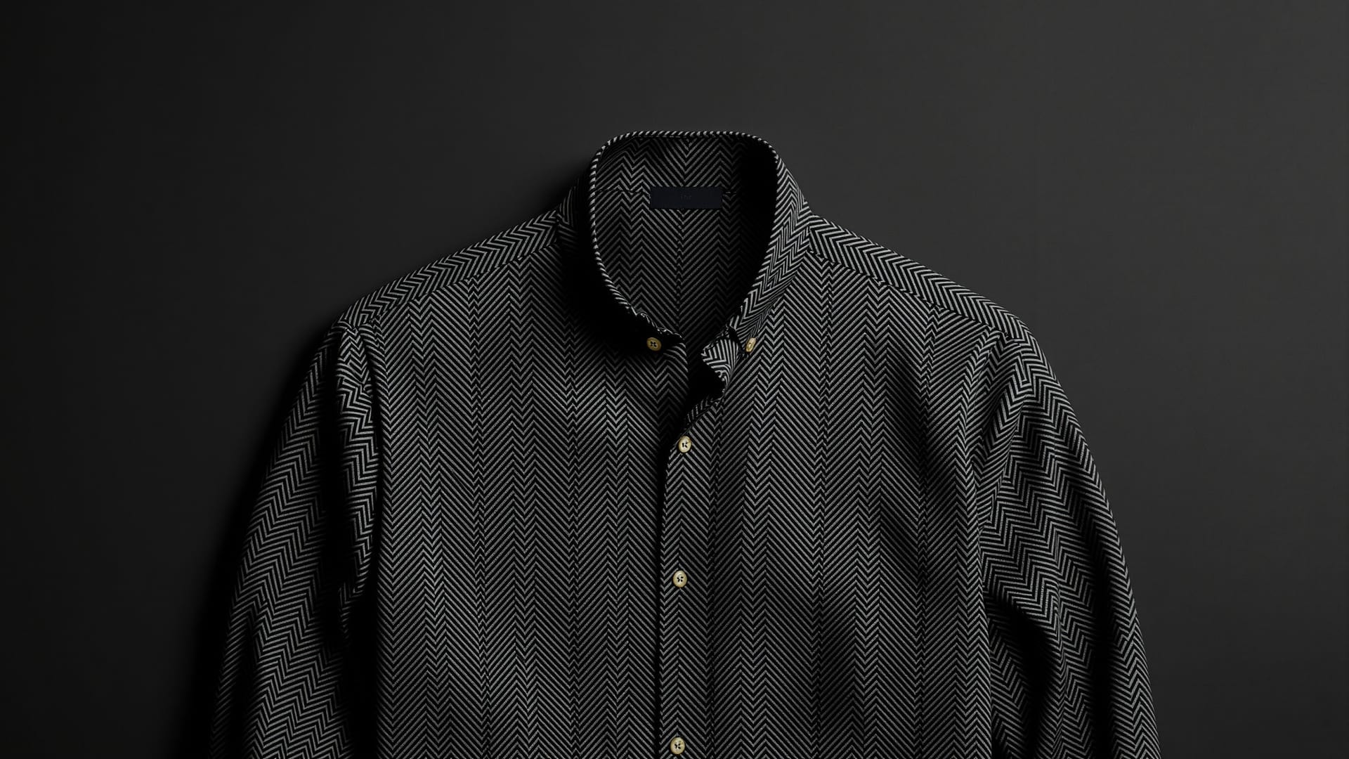 A charcoal herringbone shirt with its higher fused collar standing open at the neck